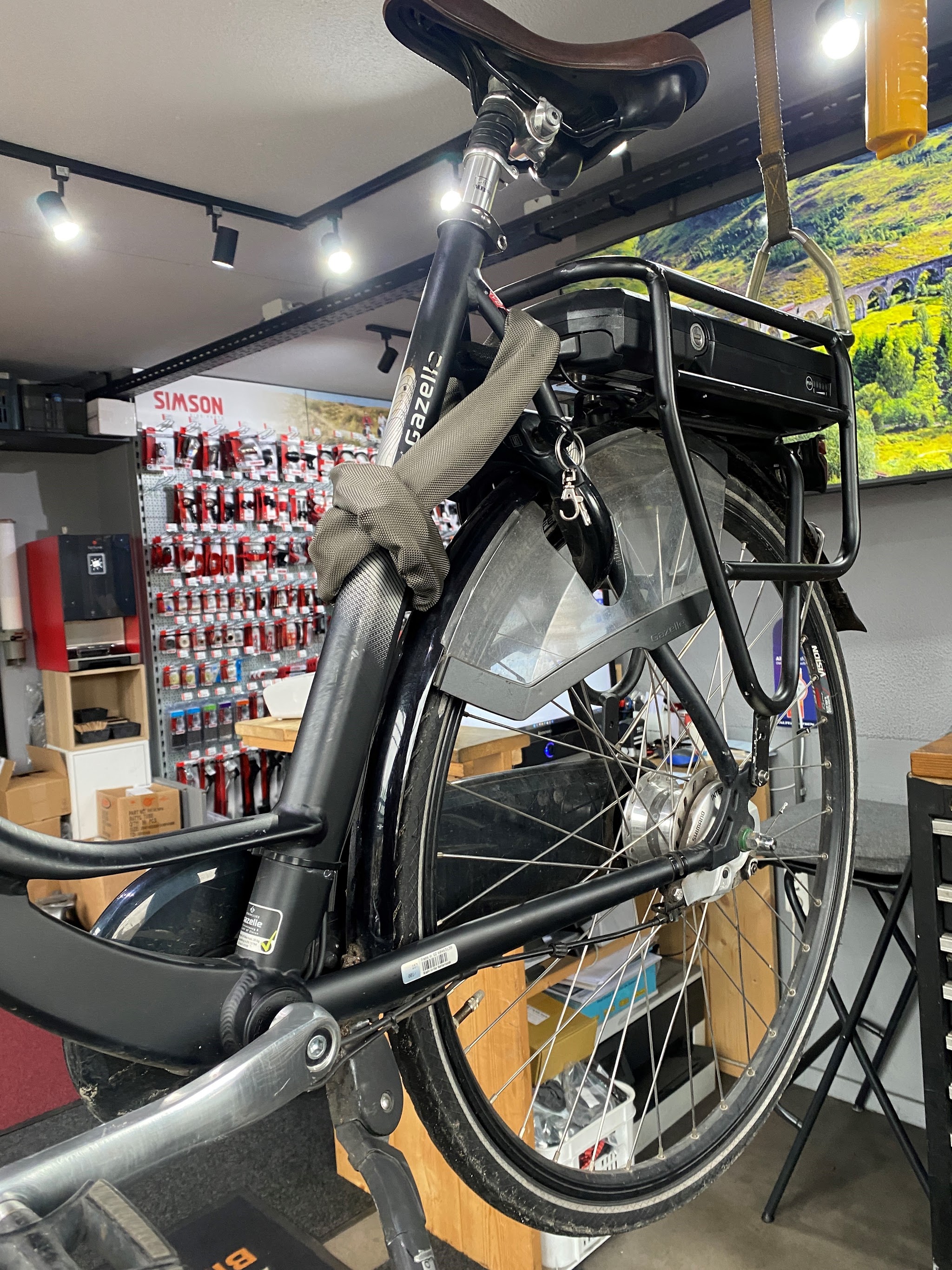 Een Gazelle e-bike in de reparatiestandaard in de winkel, met een wand vol onderdelen erachter