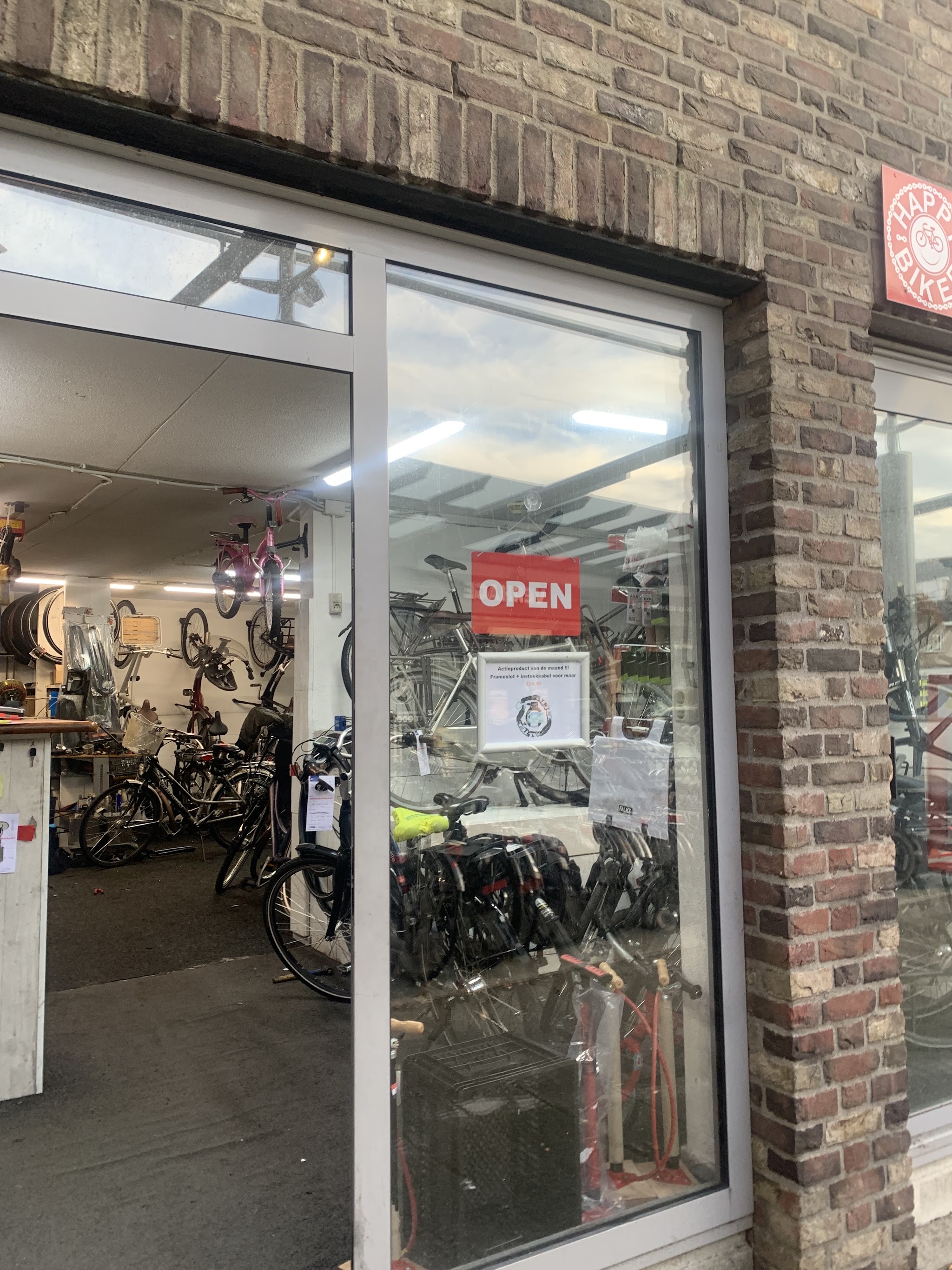 De ingang van Happy Biker met een rood OPEN-bordje en fietsen aan de muur binnen